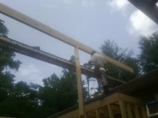 Carpenter setting a ridge beam over a new addition frame — Ice Dam Removal by Roofing Brothers in Coeburn