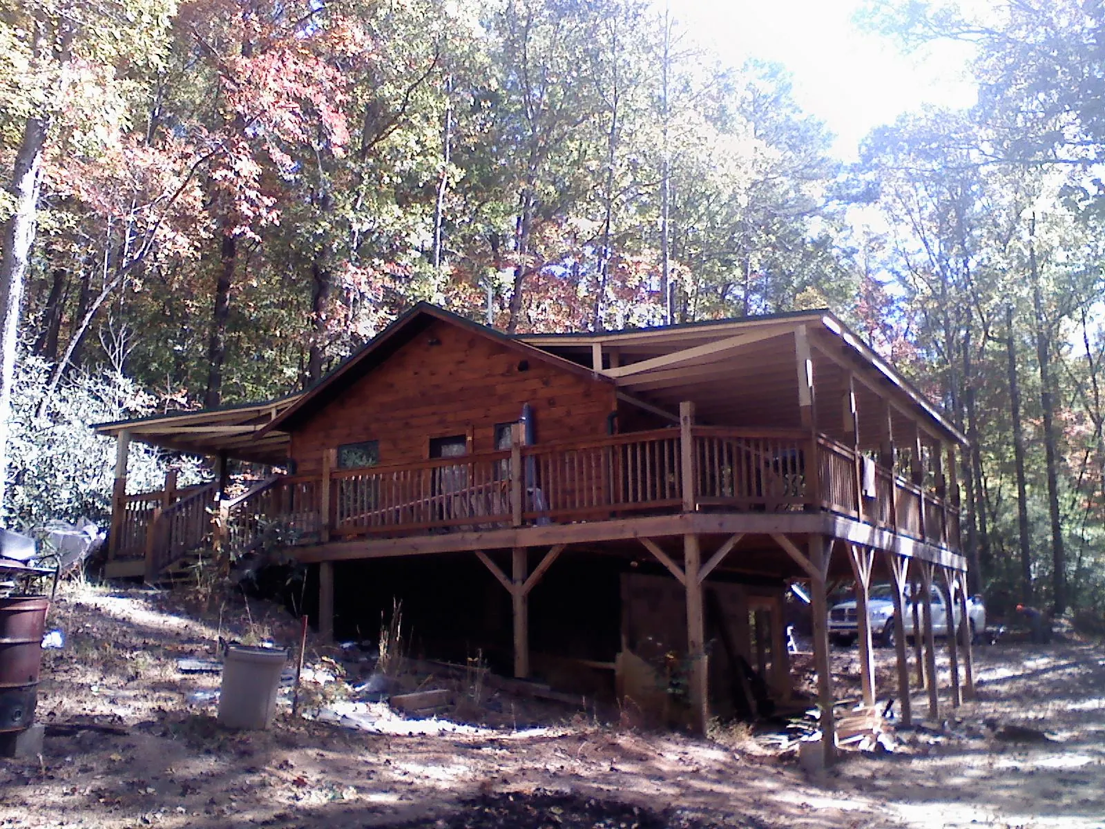 Log cabin with a wraparound porch and metal roof in the fall in Coeburn