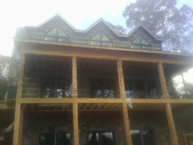 Dormers and porch framing on a large log home under construction — Roof Coating work by our crew in Coeburn