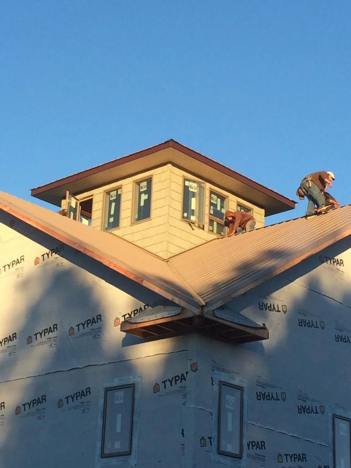 Roofers working around a rooftop cupola on a new metal roof at sunset — Roof Waterproofing in Coeburn by Roofing Brothers